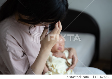 A new mother, exhausted after childbirth, holding her baby. A new mother, exhausted after childbirth, holding her baby. 141167889