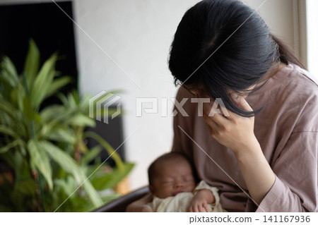 一位剛生完孩子、筋疲力盡的新手媽媽抱著她的寶寶。 一位剛生完孩子、筋疲力盡的新手媽媽抱著她的寶寶。 141167936