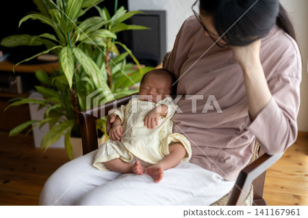 一位剛生完孩子、筋疲力盡的新手媽媽抱著她的寶寶。 一位剛生完孩子、筋疲力盡的新手媽媽抱著她的寶寶。 141167961