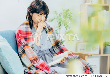 一位女士正在看書；她似乎感冒了。 141168337