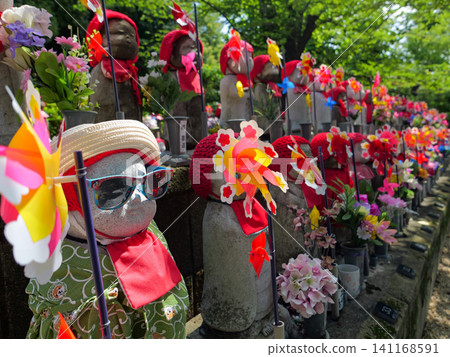 Cute Jizo statues with unique appearances stand side by side with windmills at Zojoji Temple amidst the fresh greenery. Cute Jizo statues with unique appearances stand side by side with windmills at Zojoji Temple amidst the fresh greenery. 141168591