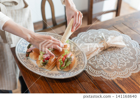 A young woman spreading mayonnaise on a homemade sandwich. A young woman spreading mayonnaise on a homemade sandwich. 141168640