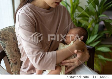 A young mother is holding her sleeping newborn baby. A young mother is holding her sleeping newborn baby. 141168889