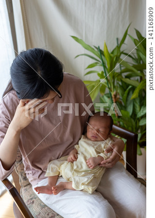 一位剛生完孩子、筋疲力盡的新手媽媽抱著她的寶寶。 一位剛生完孩子、筋疲力盡的新手媽媽抱著她的寶寶。 141168909