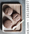 Three Whole Grain Bread Buns on Wooden Tray with Spoon in Minimal Loft Style Cafe Setting for Rustic Bakery Food Presentation 141168977
