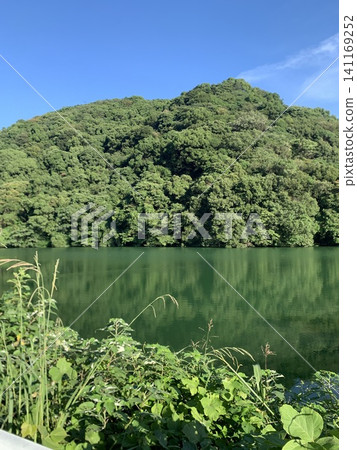 寧靜的湖面倒映著藍天和翠綠的山巒。 寧靜的湖面倒映著藍天和翠綠的山巒。 141169252