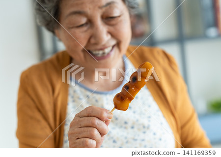 A senior woman eating mitarashi dango A senior woman eating mitarashi dango 141169359