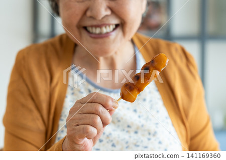 A senior woman eating mitarashi dango A senior woman eating mitarashi dango 141169360