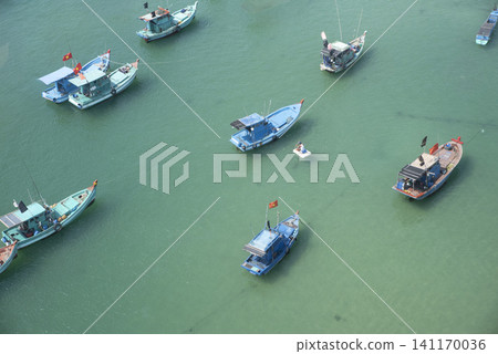 Traditional blue Vietnamese fishing boats anchored on the clear emerald green sea in Phu Quoc, Vietnam Traditional blue Vietnamese fishing boats anchored on the clear emerald green sea in Phu Quoc, Vietnam 141170036