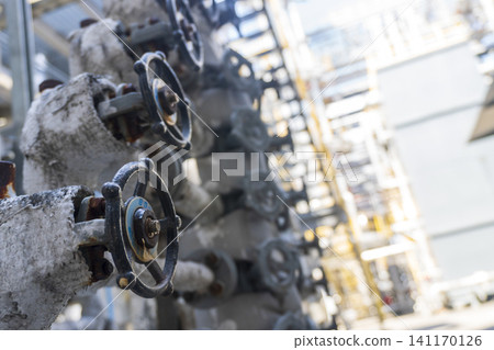 Close-up shot of industrial handwheel valves and insulated pipelines inside a chemical plant or refinery. Close-up shot of industrial handwheel valves and insulated pipelines inside a chemical plant or refinery. 141170126
