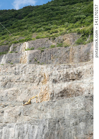 石灰岩採石場的景觀,巨大的岩壁和一台挖土機(1) 石灰岩採石場的景觀,巨大的岩壁和一台挖土機(1) 141170257