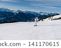 Skier standing on a groomed slope in Saalbach Austria with scenic snowy mountain peaks view 141170615