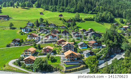 Aerial view of a picturesque Swiss village with wooden chalets in the green Alpine landscape Aerial view of a picturesque Swiss village with wooden chalets in the green Alpine landscape 141170623
