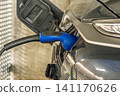 Electric vehicle charging cable plugged into a modern car port in the Netherlands, close up 141170626