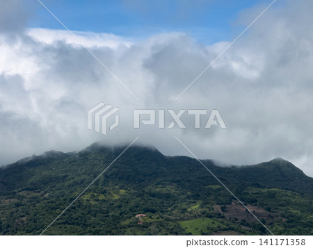 Mountains covered in clouds during daytime near a green valley Mountains covered in clouds during daytime near a green valley 141171358