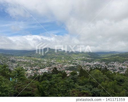 View of a valley with houses and mountains under cloudy sky near midday 141171359