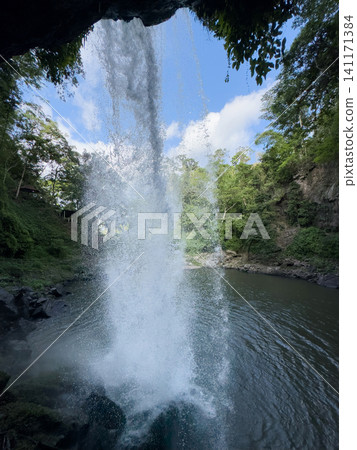 Waterfall flows into a calm pool surrounded by trees in a natural setting 141171384