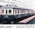 A close-up of the front of an old-style electric train (Kumoha 43 series) in the "Sky Blue" livery, stopped in a station yard from the Japanese National Railways era. 141171573