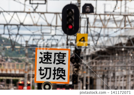 A railway speed limit indicator, a red signal, and a scene inside a train station (with background blur due to a telephoto lens). A railway speed limit indicator, a red signal, and a scene inside a train station (with background blur due to a telephoto lens). 141172071