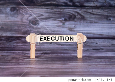 Execution symbol. A wooden stick secured by Clothespins set over beautiful Realistic Wooden Texture Background. Business and Execution concept with copy space Execution symbol. A wooden stick secured by Clothespins set over beautiful Realistic Wooden Texture Background. Business and Execution concept with copy space 141172161