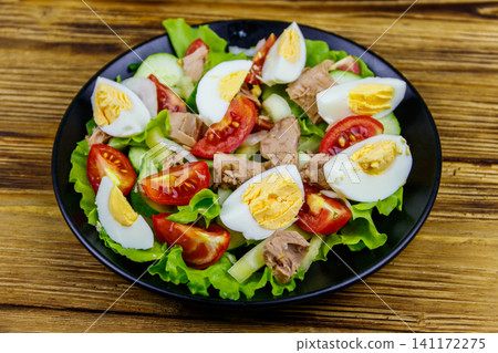 Tasty tuna salad with eggs, lettuce and fresh vegetables on wooden table Tasty tuna salad with eggs, lettuce and fresh vegetables on wooden table 141172275