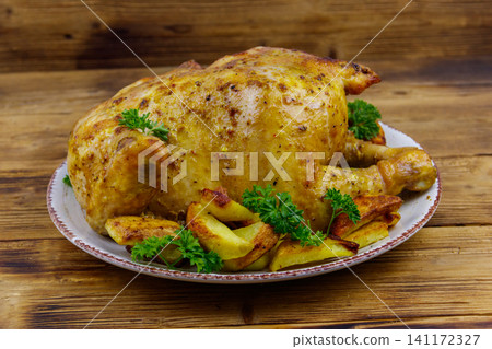 Baked whole chicken with potato on a wooden table 141172327
