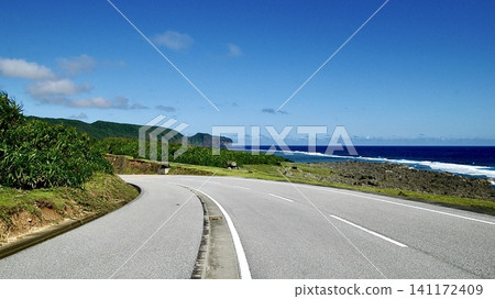 A road running along the coast of Yonaguni Island in Okinawa Prefecture, and the sea with white waves crashing against the shore. 141172409