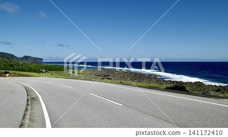 一條沿著沖繩縣與那國島海岸線延伸的公路,以及拍打著海岸的白色波浪。 一條沿著沖繩縣與那國島海岸線延伸的公路,以及拍打著海岸的白色波浪。 141172410