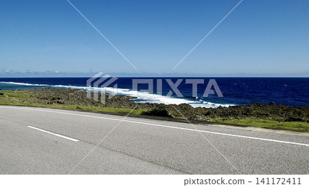 一條沿著沖繩縣與那國島海岸線延伸的公路,以及拍打著海岸的白色波浪。 一條沿著沖繩縣與那國島海岸線延伸的公路,以及拍打著海岸的白色波浪。 141172411