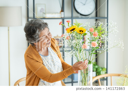 A senior woman arranging flowers at home A senior woman arranging flowers at home 141172863