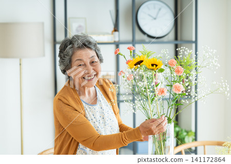 A senior woman arranging flowers at home A senior woman arranging flowers at home 141172864