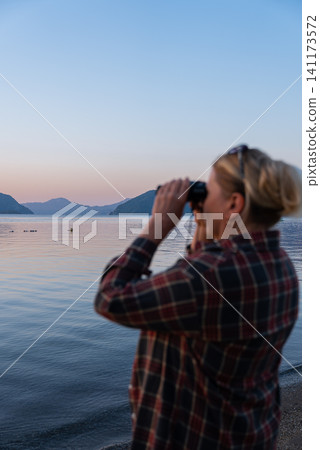 Woman Looking Through Binoculars on Marmaris Waterfront at Golden Hour 141173572