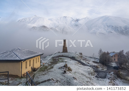 Ancient stone watchtower in Sioni village, Kazbegi region, Georgia, surrounded by snow and mountain mist. 141173852