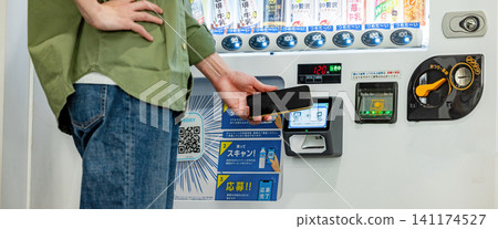 A man using his smartphone at a vending machine. A man using his smartphone at a vending machine. 141174527