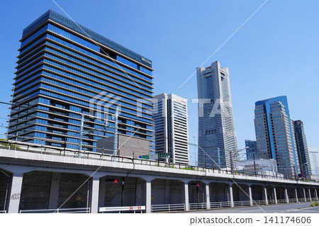 The cityscape of Yokohama's Minato Mirai district, with its towering skyscrapers and elevated railway tracks, stands out against a clear blue sky. The cityscape of Yokohama's Minato Mirai district, with its towering skyscrapers and elevated railway tracks, stands out against a clear blue sky. 141174606