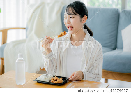 一位年輕女子正在客廳吃午餐 141174627