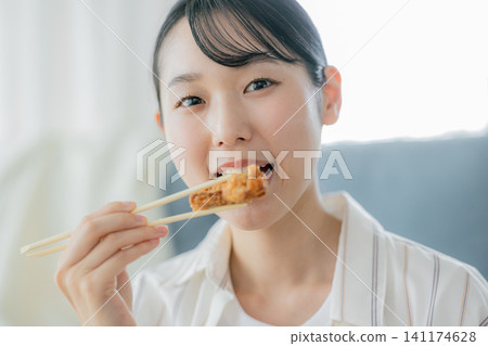 A young woman eating fried chicken A young woman eating fried chicken 141174628