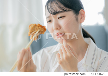 一位年輕女子正在吃炸雞 141174629