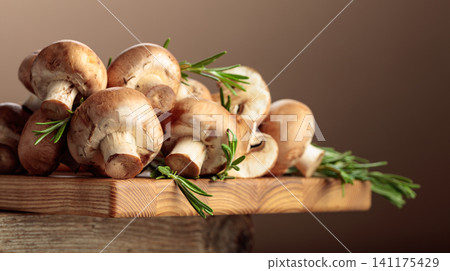 Mushrooms with rosemary on a wooden cutting board. Mushrooms with rosemary on a wooden cutting board. 141175429