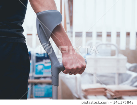 Injured man trying to walk on ?rutches. Injured man trying to walk on ?rutches. 141175942