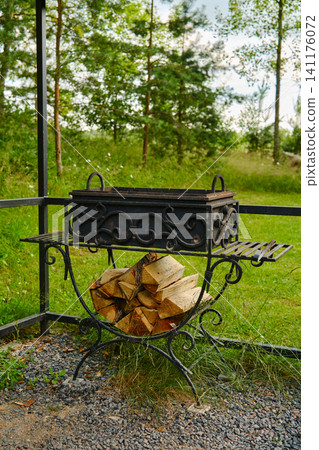 Outdoor fire pit with stacked wood in garden area surrounded by trees and grass Outdoor fire pit with stacked wood in garden area surrounded by trees and grass 141176072