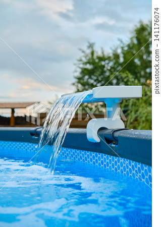 Water flowing from pool water pump in backyard during summer afternoon Water flowing from pool water pump in backyard during summer afternoon 141176074