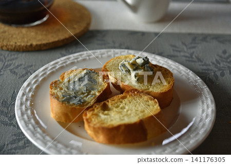 Blue cheese on baguette on white plate. Blue cheese on baguette on white plate. 141176305
