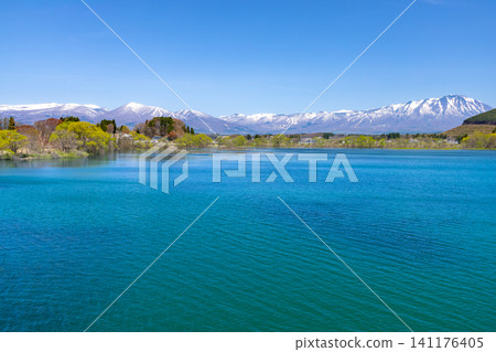 從岩手縣岩手郡雫石町雫石川上的雫石湖水庫-雫石湖上的元雫橋上,可以看到湖面藍色的湖面上白雪皚皚的岩手山和高倉山。 從岩手縣岩手郡雫石町雫石川上的雫石湖水庫-雫石湖上的元雫橋上,可以看到湖面藍色的湖面上白雪皚皚的岩手山和高倉山。 141176405