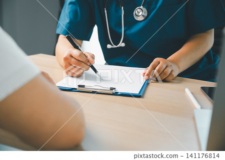 Healthcare professional writing medical notes on a clipboard during patient consultation in a clinic, doctor appointment, diagnosis, health checkup, and medical care concept. Healthcare professional writing medical notes on a clipboard during patient consultation in a clinic, doctor appointment, diagnosis, health checkup, and medical care concept. 141176814