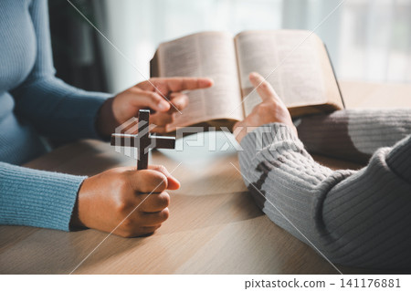 People praying with folded hands over open Bible during Bible study, showing Christian fellowship, spiritual support, devotion, hope and peaceful faith. People praying with folded hands over open Bible during Bible study, showing Christian fellowship, spiritual support, devotion, hope and peaceful faith. 141176881