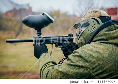 Man with gun playing at paintball. Outdoors 141177097