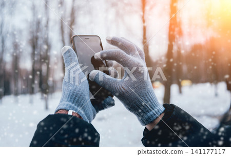 Man using smartphone in winter with gloves for touch screens 141177117