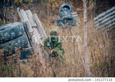 Man with gun playing at paintball. Outdoors Man with gun playing at paintball. Outdoors 141177118