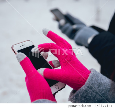 Couple using smartphone in winter with gloves for touch screens 141177125